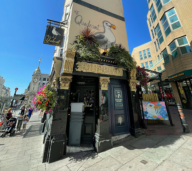 The exterior of a British pub with beige walls and a giant seagull painted above the entrance