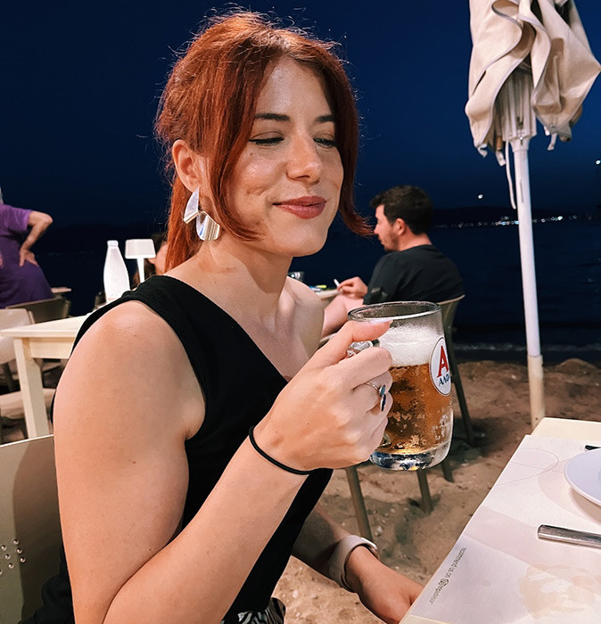 enjoying life abroad A female expat holding a beer next to a beach