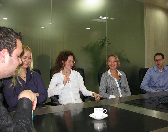 5 young adults sitting around a large table in an office