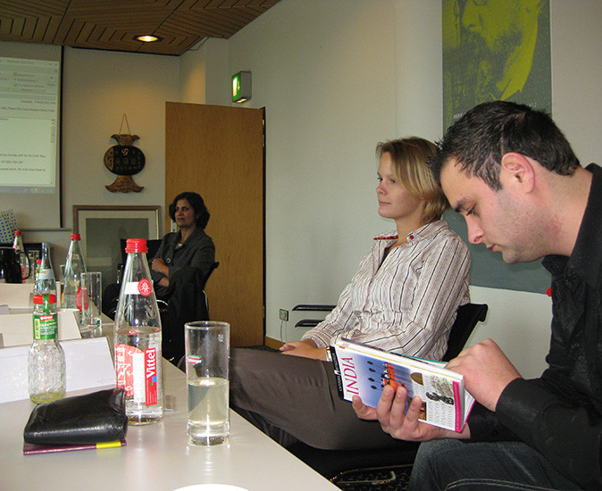 3 people sitting at a large table in an office setting