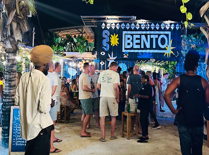 Various people sitting and standing at an outdoor bar in Zanzibar