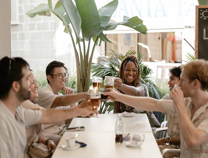 6 digital nomads sitting around a white table, holding up their glasses to cheers