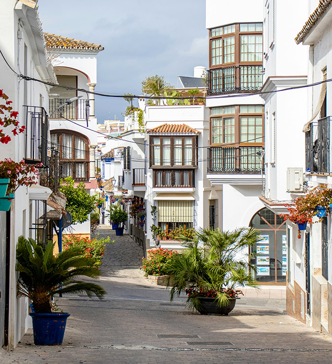 A narrow Spanish street with 2 and 3-storey whitewashed houses on both sides