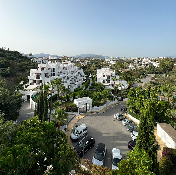 A residential area of Estepona showing white houses surrounded by greenery and a street with parked cars