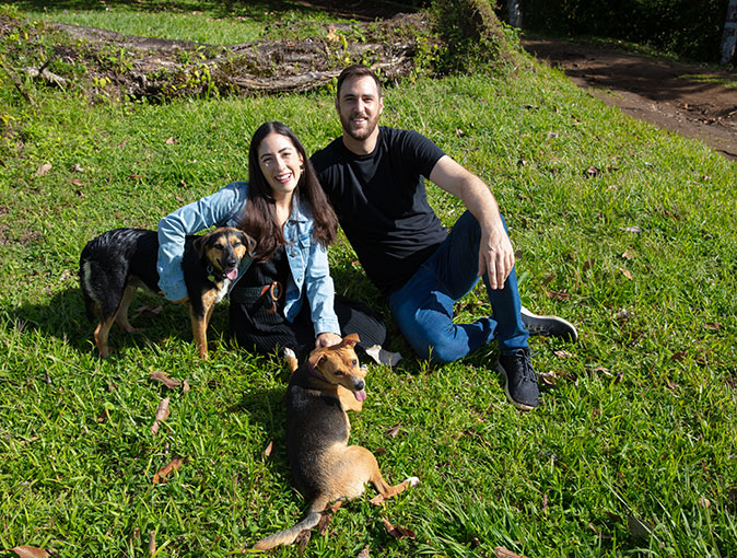 A couple with 2 dogs sitting in a green field in Costa Rica