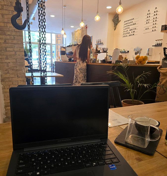 Best cafes to work from in Valencia A laptop on a table in a cafe with a counter and a woman in the background