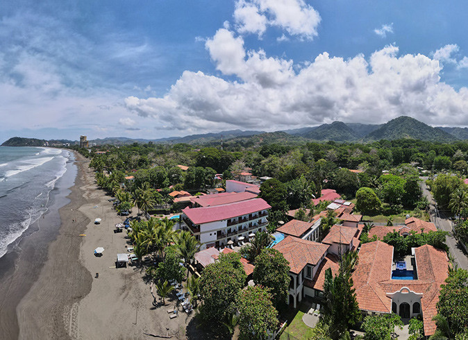 Areal view of a coastal town in Costa Rica showing a sandy beach, several houses and greenery