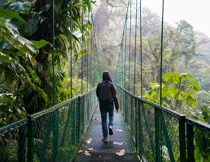 A man crossing a bridge wearing a rain coat