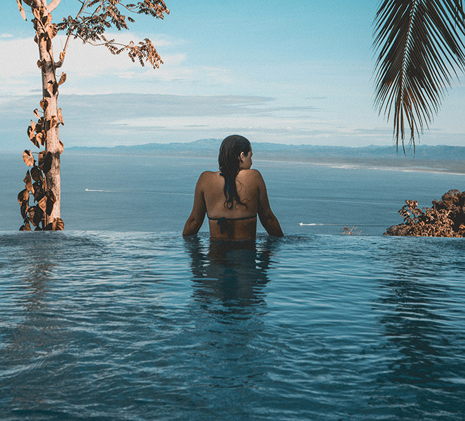 An American woman in a swimming pool looking out over the coast of Costa Rica
