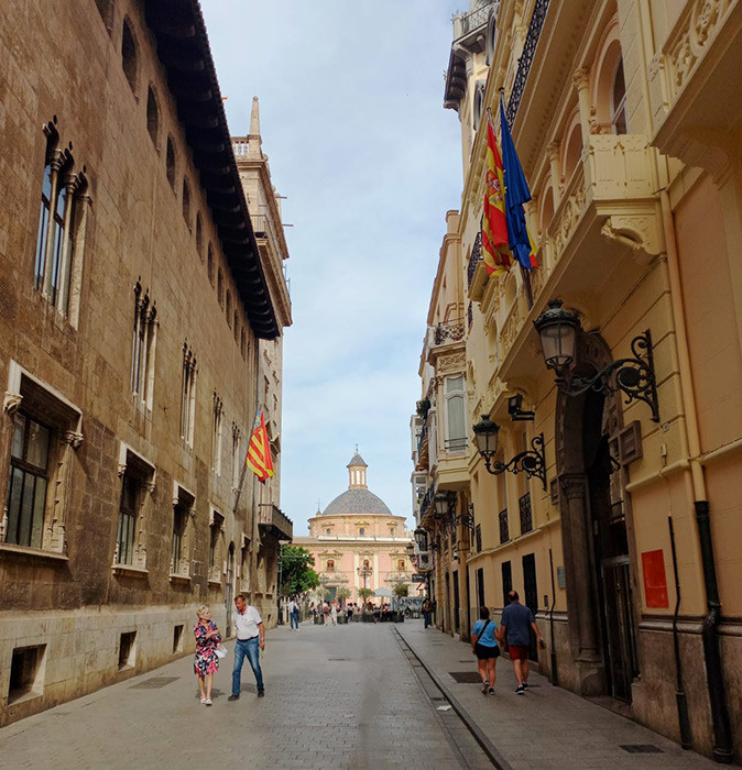 Safety in Valencia for digital nomads and remote workers A narrow street lined with historic buildings and a large domed church in the background