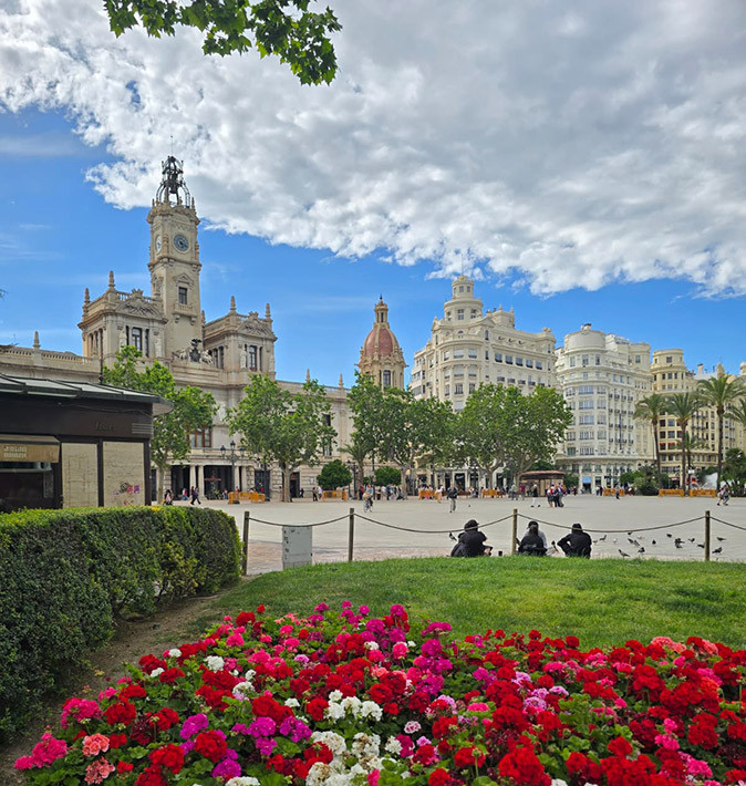 Valencia, a good city for digital nomads Flowers and grass in front of a city square with historic buildins