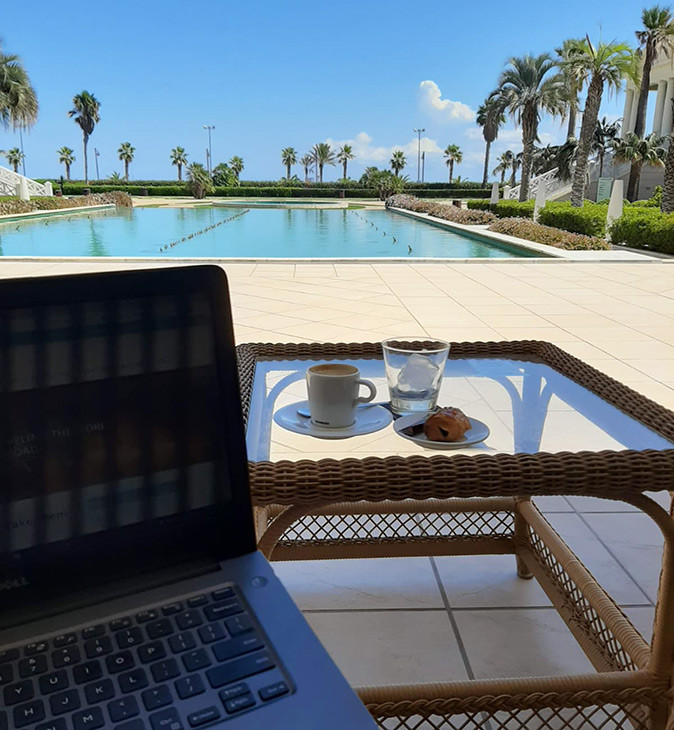 Best places to work from in Valencia A laptop next to a coffee with a large fountain and palmtrees in the background