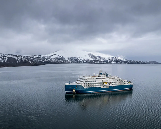 An antarctica cruise to the Ross Sea A large cruise ship surrounded by water and a snow covered landscape