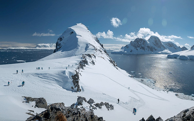 Excursion on an Antarctic cruise to the Ross Sea A group of people walking on a steep, snow covered mountain in antarctica