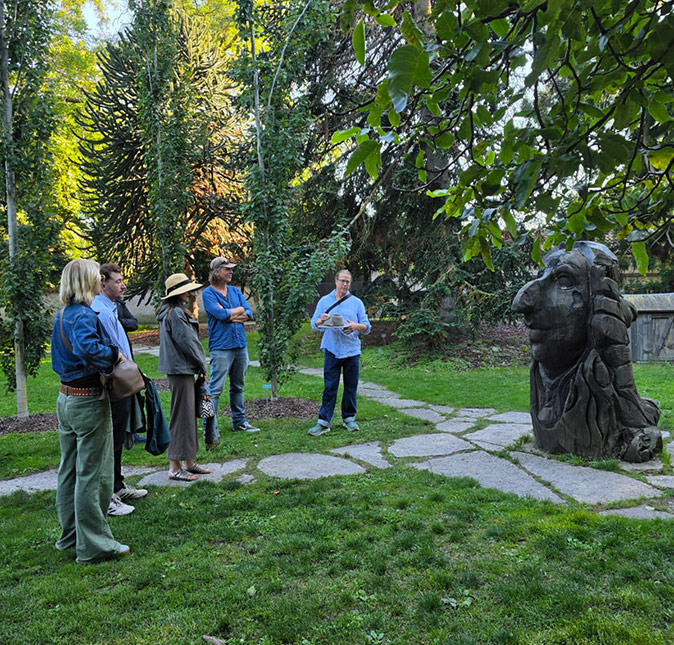 Traveling as part of a coworking trip A group of people with a tour guide standing next to a statue in a park