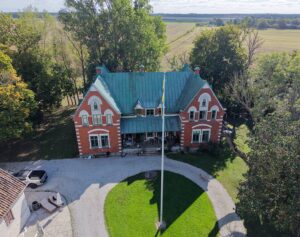 Drone shot of a historic red home with a green roof in a Swedish landscape on the island of Gotland