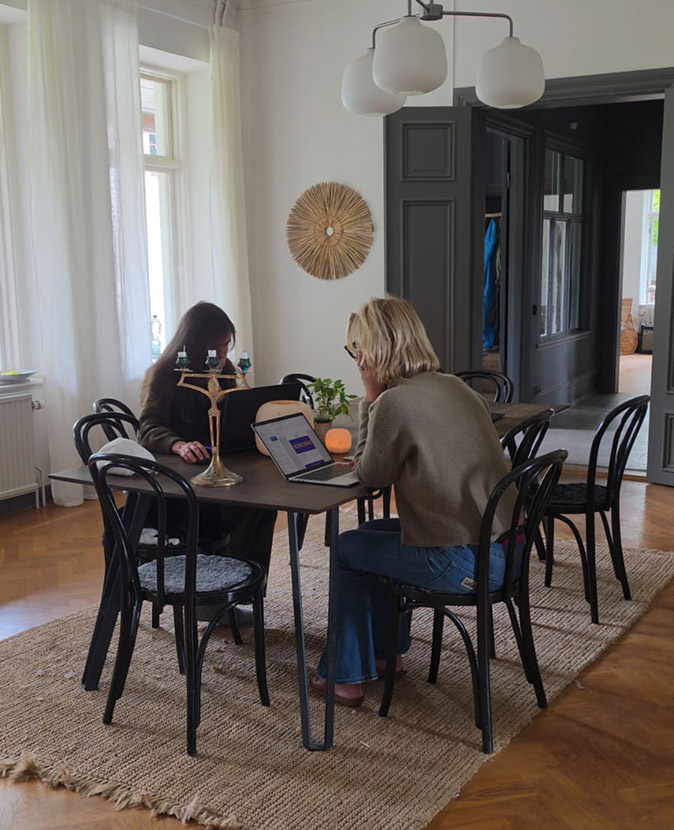 Working together at a coliving retreat in Sweden 2 women sitting at a table working on their laptops