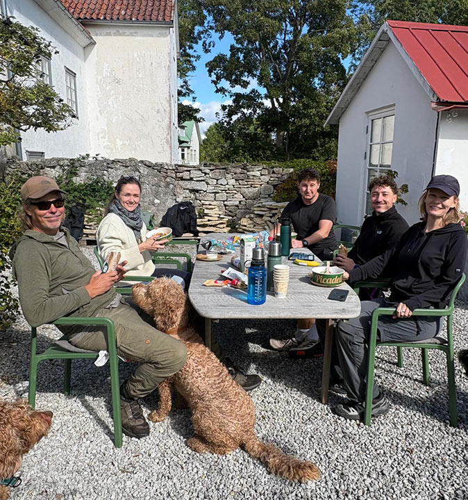 Enjoying the weekend while working remotely from Sweden 5 people sitting around a table in a garden having lunch