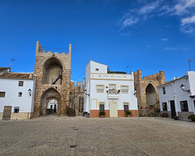 The town of Buñol, where La Tomatina happens every year A typical historic Spanish town square showing parts of an old city gate and whitewashed buildings