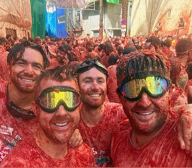 The La Tomatina tomato throwing festival in Bunol, Spain 4 men in a crowd of people all covered in tomato pulp at Spain's annual tomato festival La Tomatina